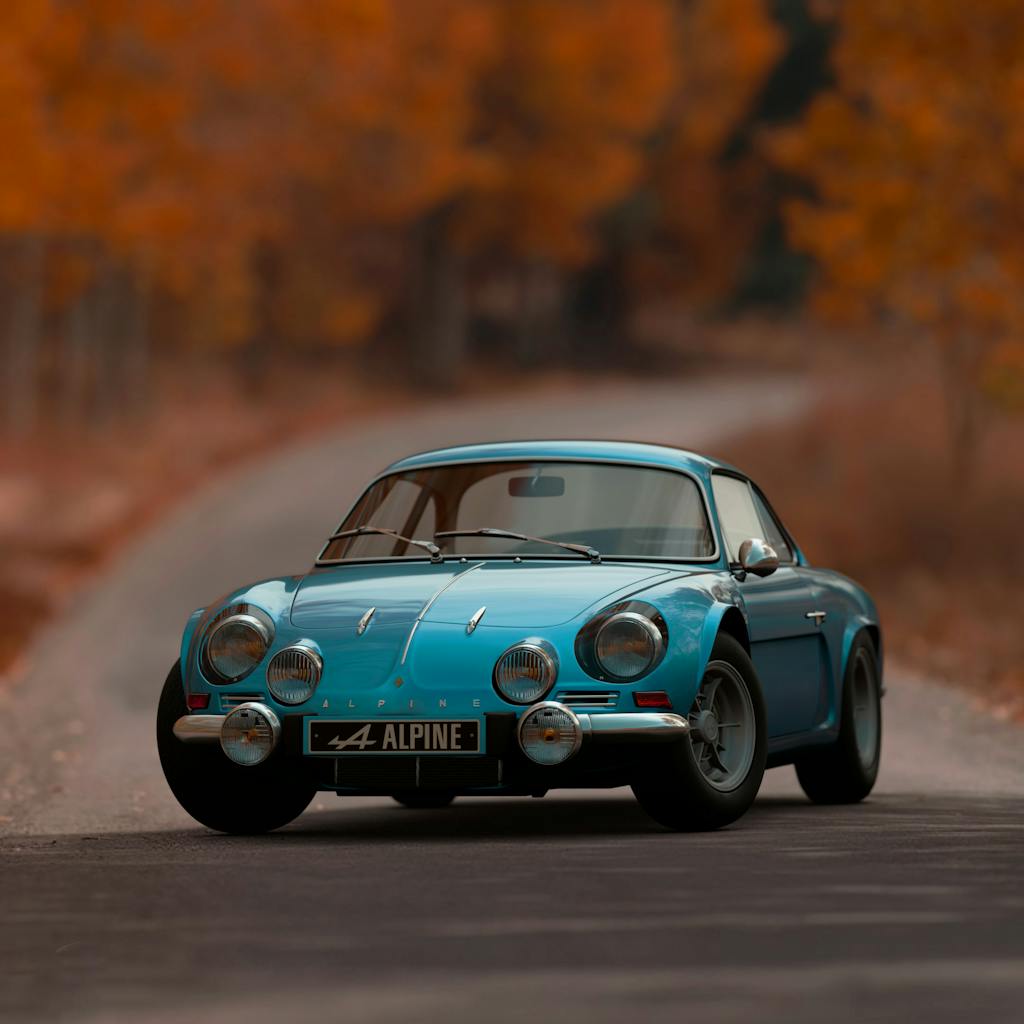 Classic Alpine A110 sports car driving on an autumn road with vibrant foliage.