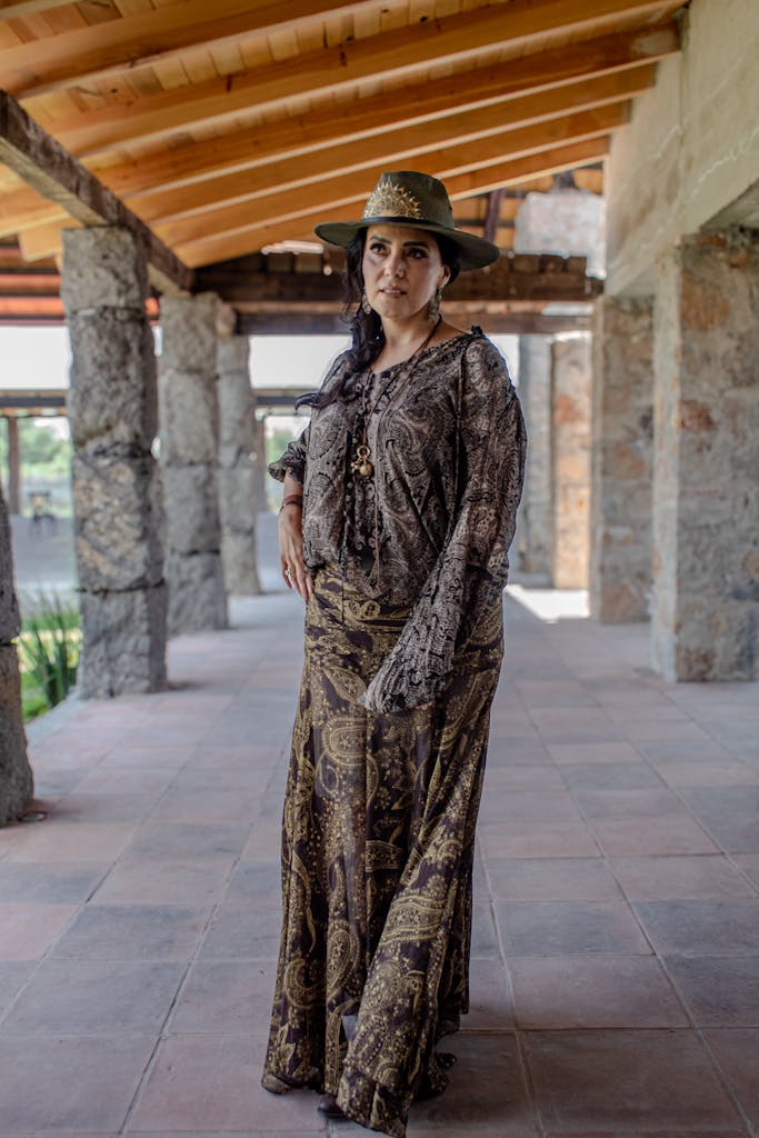 Elegant woman in patterned attire poses in a rustic outdoor corridor in Querétaro, Mexico.