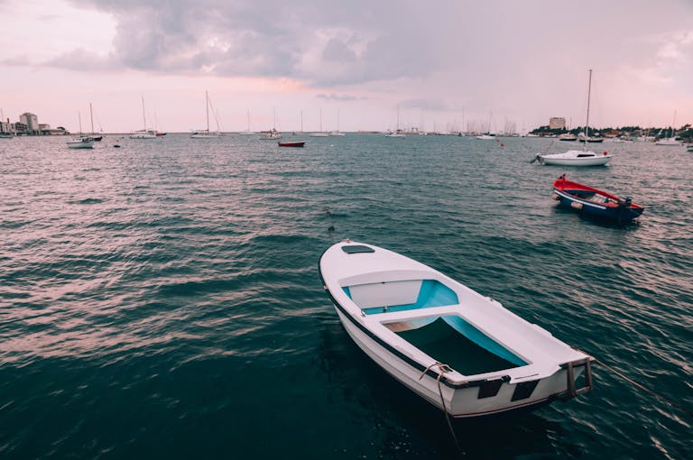 Serene seascape with boats drifting on the Adriatic Sea under a cloudy sky.