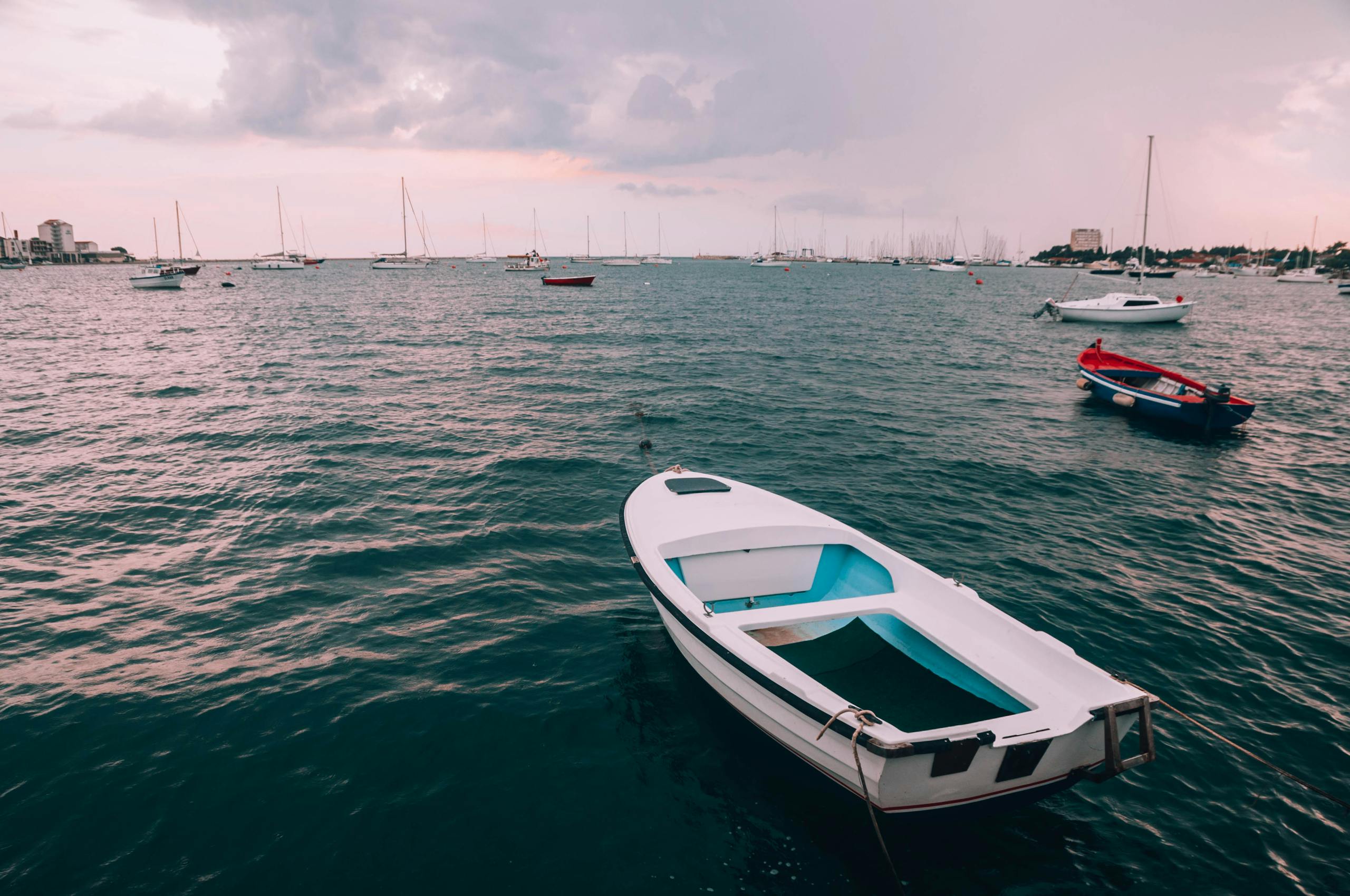 Serene seascape with boats drifting on the Adriatic Sea under a cloudy sky.